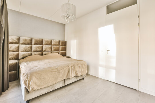 a bedroom with a bed and a chandel on the wall in front of the bed is an open door