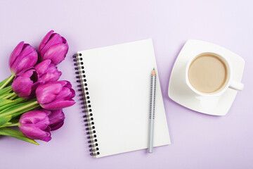 Blank notepad, pen, coffee cup and purple tulips on lilac background. Top view, flat lay, mockup