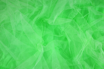 Lime color silk fabric with light green wrinkled organza background. top view.