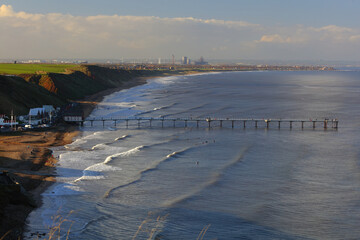 Panoramic Landscape image of Saltburn on a sunny afternoon with lots of people surfing. Saltburn, North Yorkshire, England, UK.