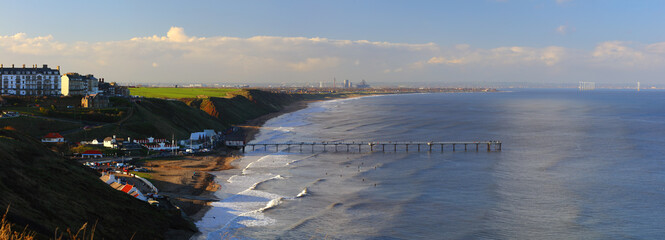 Panoramic Landscape image of Saltburn on a sunny afternoon with lots of people surfing. Saltburn, North Yorkshire, England, UK. - obrazy, fototapety, plakaty