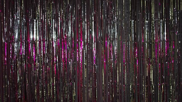 Silver rain from tinsel with pink light. Beautiful silver background with shiny silver glitter sparkles. Festive mood. Christmas or holiday theme. 