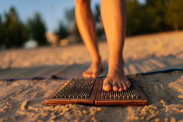 Close-up of feet unrecognizable female stepping on Sadhu Nail board during concentration meditation...