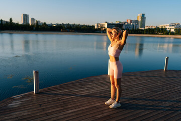 Attractive athletic woman exercising and stretching neck for warming up before running or working...
