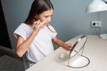 Teen girl inserts blue eye lens in eye