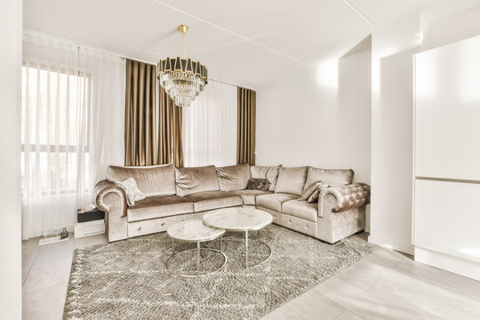 a living room with couch, coffee table and chandels on the wall in the room is very white