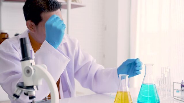 4K, male teacher who teaches science, wears white glue shirt, sitting in science room, Was stressing about experiment, before teaching experiment students for experiment in class, practice period.