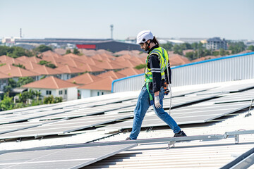 Male engineer installing or checking the working condition of solar panels on the roof or at the...