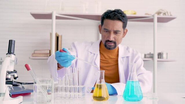 4K, male teacher who teaches science, wears white glue shirt, sitting in science room, being serious, with finding results in trials, in order teach children in classroom in science class, practical.
