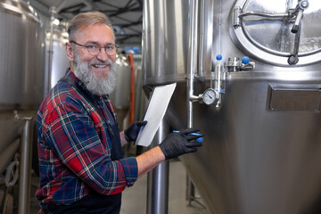 Brewery worker checking the pressure in tanks with beer