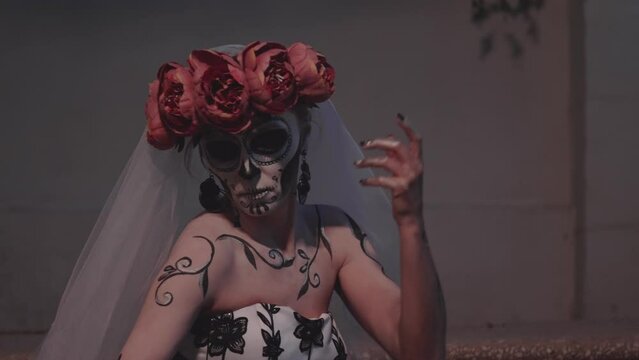 Woman with sugar skull makeup gesturing with her hands. Day of the Dead festival in Mexico