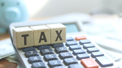 Tax season with wooden letter blocks, calculators, pens on dollar treasuries.