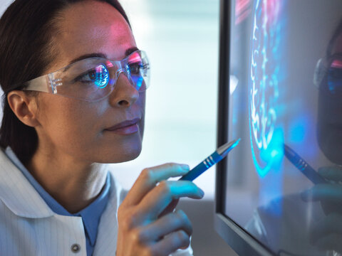 Scientist in glasses looking at screen with medical brain data