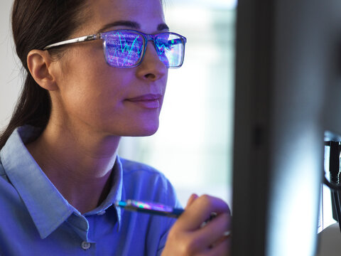 Female expert in glasses looking at screen with financial data