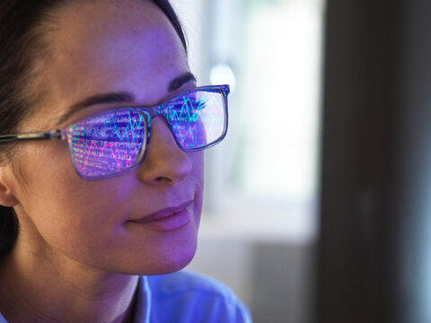 Female expert in glasses looking at screen with financial data - Powered by Adobe
