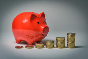 Anwachsende Münzstapel mit Euro Münzen stehen neben einem roten Sparschwein