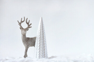 The figure of a reindeer, a deer stands near the Christmas tree, the decor of a Christmas card.