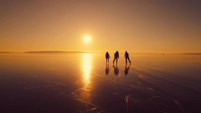 Three friends are skating into the sunset. A giant natural skating rink formed on a frozen river.