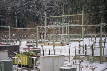 Fototapeta na wymiar Electrical substation in winter with snow covered transformers and isolators