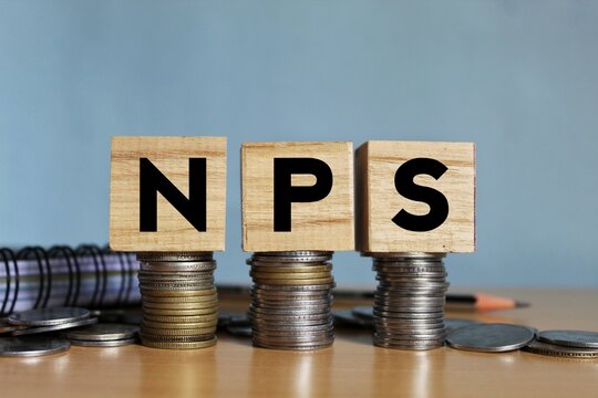 NPS or national pension scheme with wooden bids or blocks on Indian rupees notes.