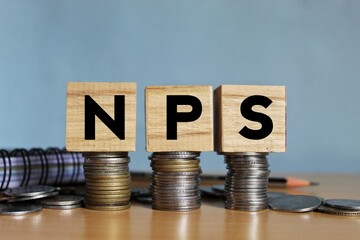 NPS or national pension scheme with wooden bids or blocks on Indian rupees notes. - obrazy, fototapety, plakaty