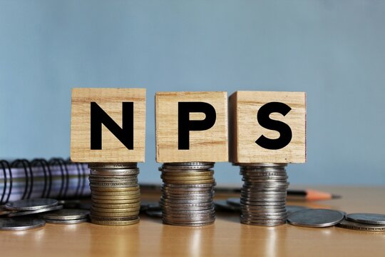 NPS or national pension scheme with wooden bids or blocks on Indian rupees notes.