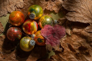 Winter mood- toys for decorating the Christmas tree on a background of oak leaves