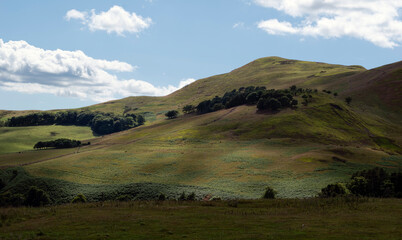 Gentle afternoon light through clouds on green rolling hills in Scotland