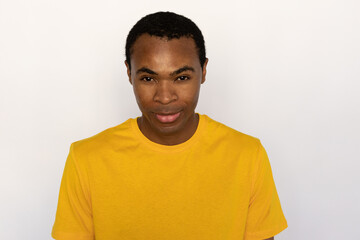 Portrait of confident young man looking at camera. African American guy wearing yellow T-shirt posing against white background. Confidence concept