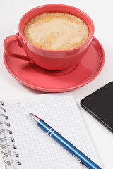 Smartphone, coffee with milk and notepad for writing notes. Work or relaxation with mobile phone. White background