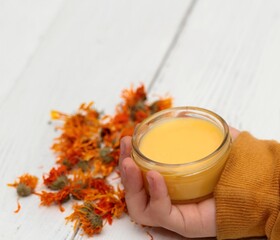 Boy´s hand holdind calendula ointment, copy space. Medicinal cream from dried marigold flowers...