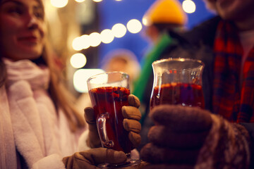 Close-up hands in mittens with mug of hot mulled wine. Happy holidays, national traditions, winter street fairs, Christmas concept.