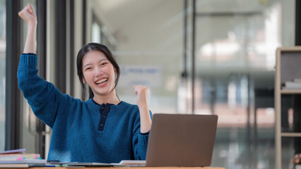Young Asian women celebrate success or happy poses with a laptop.