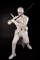Combat ninja posing with a sword on a black background