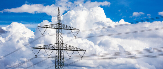 a high voltage road in front of big clouds and blue sky panorama