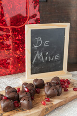 Heart shaped chocolate and pomegranate candies on an olive wood board.  Be mine on a chalkboard and...