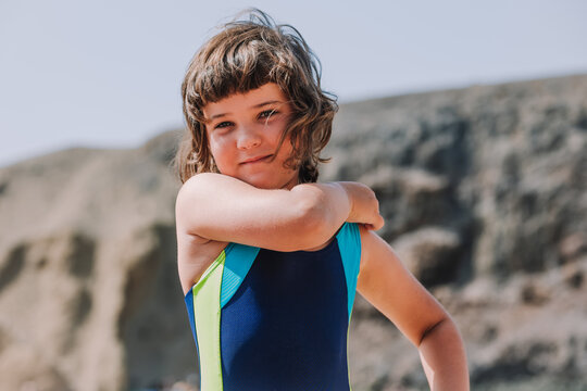 Cute girl in swimsuit standing against rocky cliff