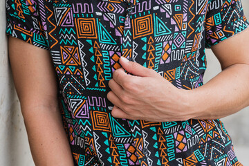 Crop man buttoning up colorful shirt