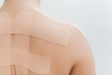 Women's body with kinesio tape on the back and shoulders. Kinesiology taping concept. White background. Close-up view