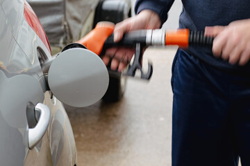 Man refueling a car in Europe with a pistol in his hand. Gas station - refueling, diesel and...