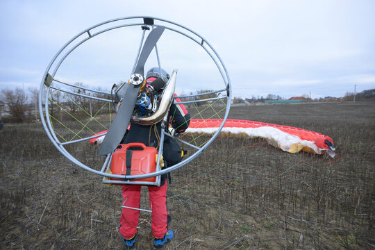 Powered paragliding. Man paramotorist making preparations for flight, paramotor engine propeller and wing set and ready