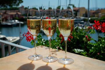 Drinking of French brut champagne sparkling wine in glasses in yacht harbour of Port Grimaud near Saint-Tropez, French Riviera vacation, France