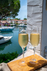 Drinking of French brut champagne sparkling wine in glasses in yacht harbour of Port Grimaud near Saint-Tropez, French Riviera vacation, France
