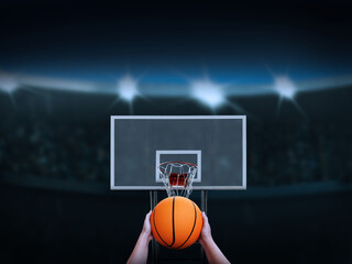 Hand holding a basketball about to shoot it into the basketball backboard There is an amphitheater...