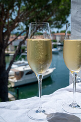 Drinking of French brut champagne sparkling wine in glasses in yacht harbour of Port Grimaud near Saint-Tropez, French Riviera vacation, France