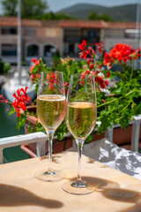 Drinking of French brut champagne sparkling wine in glasses in yacht harbour of Port Grimaud near Saint-Tropez, French Riviera vacation, France