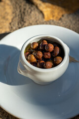 Small pickled brown olives as pairing for red dry beaujolais wine served outdoor in France, Beaujolais region.