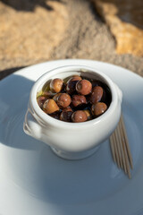 Small pickled brown olives as pairing for red dry beaujolais wine served outdoor in France, Beaujolais region.