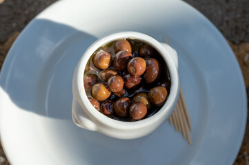 Small pickled brown olives as pairing for red dry beaujolais wine served outdoor in France, Beaujolais region.