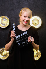 Woman holding video film clapboard cinematography lifestyle. Creative lamps on the background....